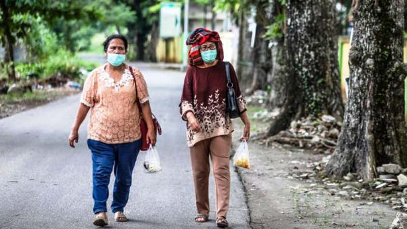 Ilustrasi: Dua orang perempuan berjalan di sebuah Jalan di Medan, Sumatera Utara dengan menggunakan masker wajah