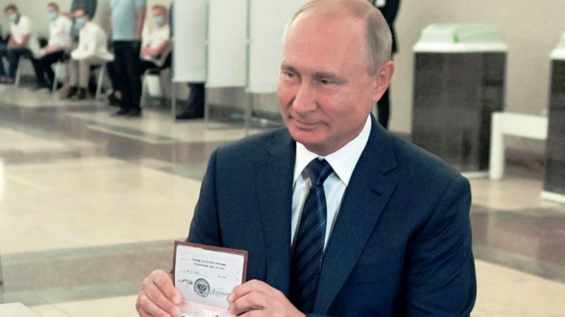 Presiden Rusia Vladimir Putin menunjukkan paspornya kepada petugas pemungutan suara saat tiba di tempat pemungutan suara di Moskow, Rusia, 1 Juli 2020