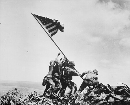 Pasukan Amerika Serikat mengibarkan bendera di puncak Gunung Suribachi selama Pertempuran Iwo Jima. Momen bersejarah itu dipotret oleh fotografer Associated Press Joe Rosenthal. (Sumber: Wikimedia Commons)