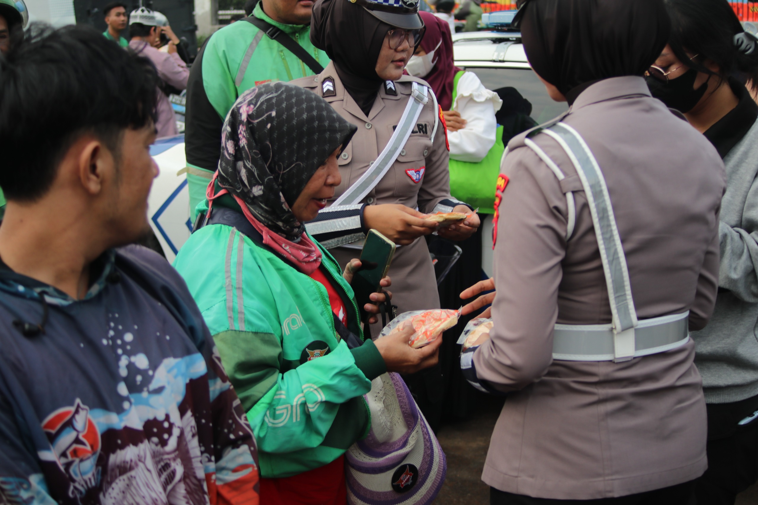 Anggota Polantas saat membagikan roti dan air mineral kepada para driver ojol yang mengikuti aksi demonstrasi. (foto: Sulindo/Iqyanut Taufik)